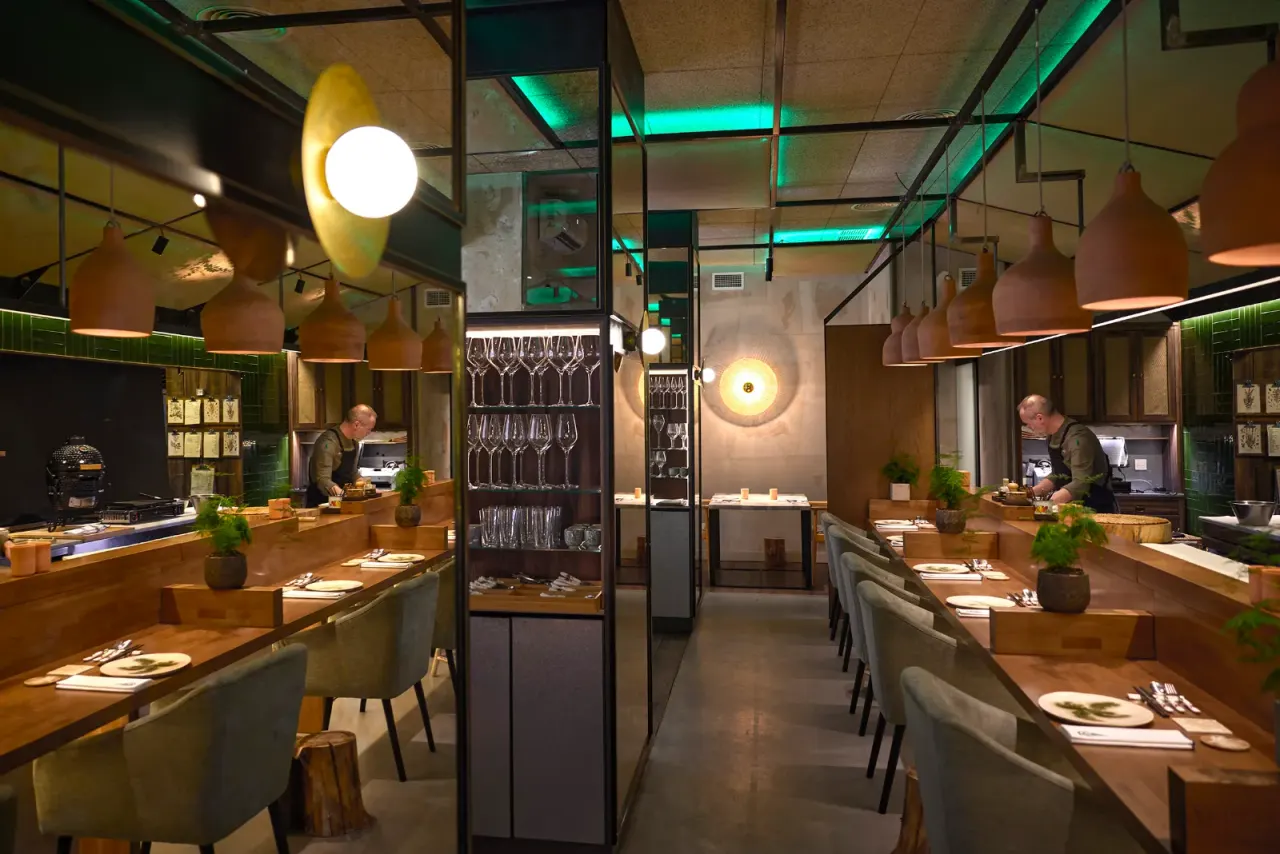 Pasillo del comedor con las copas puestas en las mesas y la cristalería al fondo