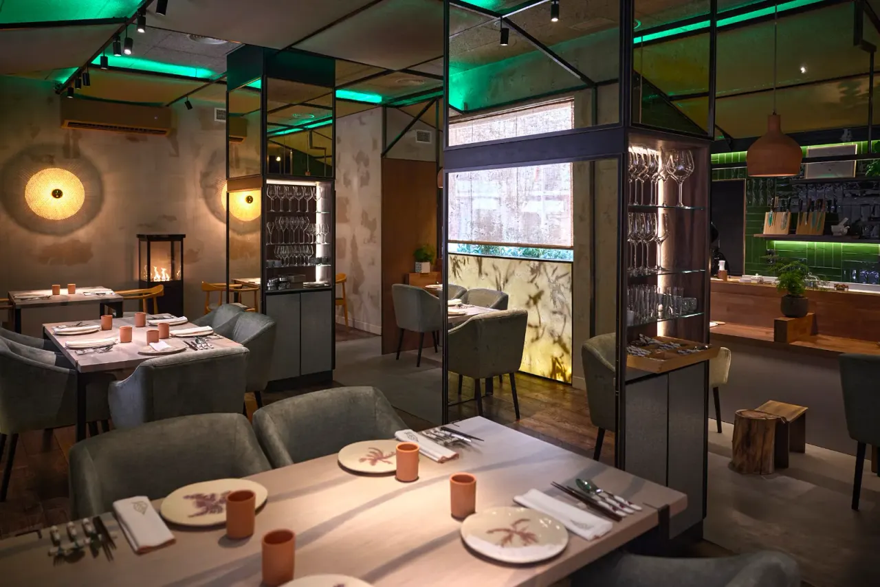 Mesa vestida del comedor de El Invernadero con la luz verde de la sala al fondo
