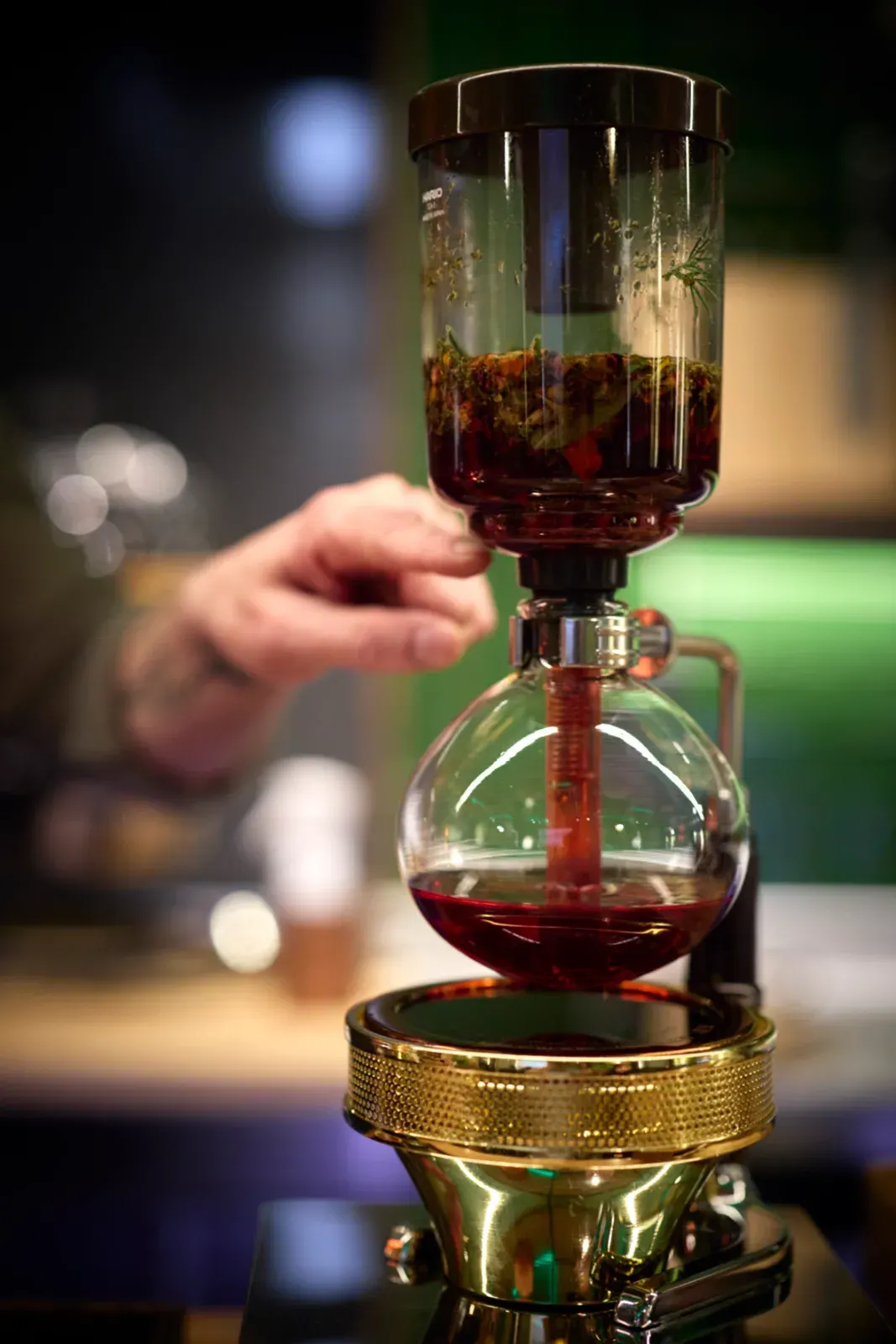 La infusión cayendo al balón de cristal del sifón durante el servicio