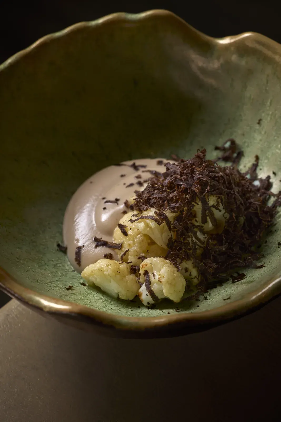 Coliflor con café rallado por encima, en plato de cerámica verde