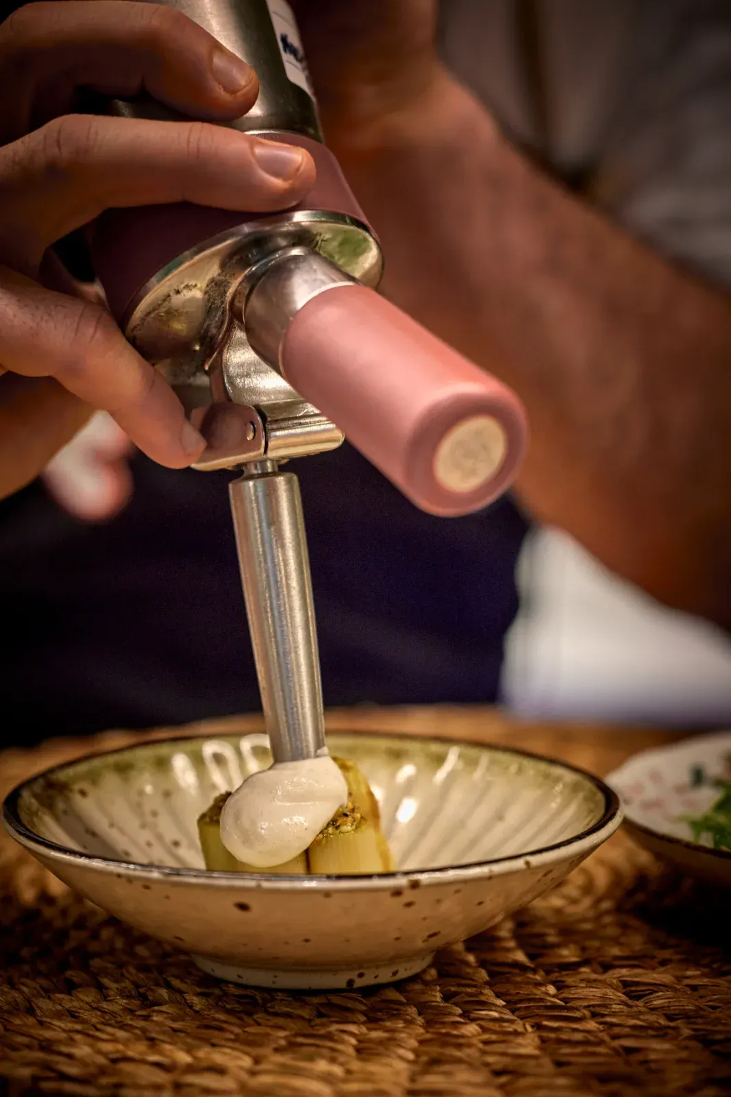 Un cocinero corona el pase con espuma de sifón, en un cuenco de cerámica