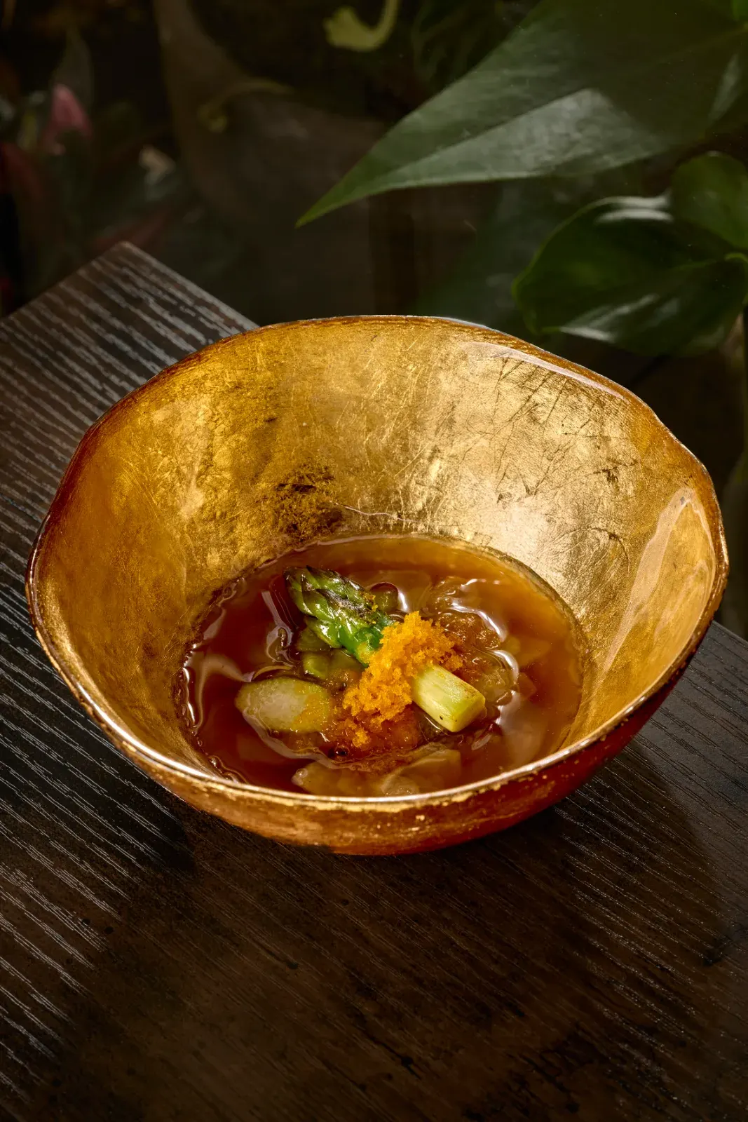 Espárrago verde con caldo y huevas servido en cuenco dorado