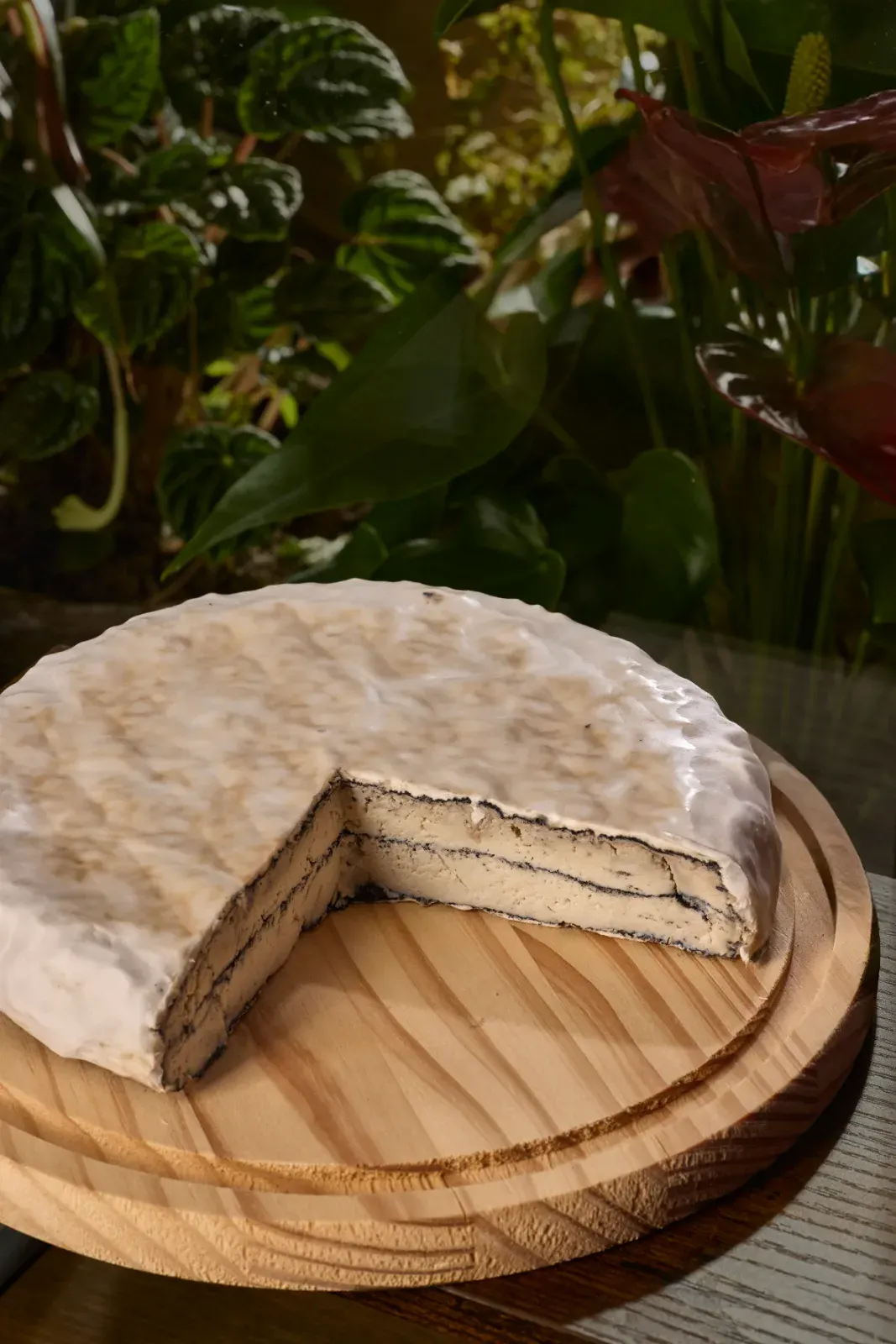 La tarta de queso de la casa, entera y con el primer corte, sobre tabla de madera
